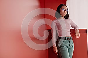 Asian Woman Wearing Eyeglasses and Looking at Camera Standing in Red Space