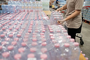 Asian woman wearing face mask,choosing packs of fresh water,beverage and food,people panic buying and hoarding during the Covid-19