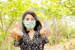 Asian woman wearing face mask outdoors to prevent virus covid-19  with thump up hand