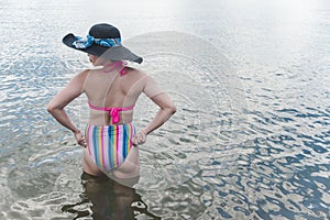 An asian woman wearing a fashionable high waist bikini in almost waist deep water. Vacation getaway and summer fashion theme