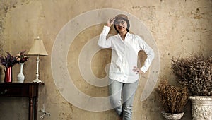 Asian woman wearing flat cap hat white shirt and jeans on vintage style sepia wall background