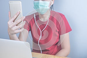 Asian woman wearing hygiene protective mask to protect COVID19, making facetime video calling with smartphone at home, social