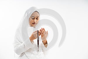 Asian woman wearing ihram clothes praying with prayer beads