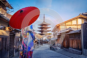 Asian woman wearing a Japanese kimono holding a red umbrella visits the Yasaka Pagoda