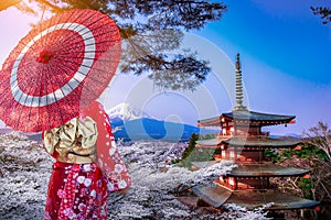 Asian woman wearing japanese traditional kimono at Chureito red  pagoda and Fuji mountain in cherry blossom festival, Japan