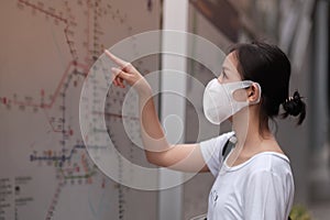 Asian woman wearing a mask looking at a map sign