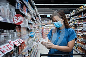 Asian woman wearing mask over her face while grocery shopping in supermarket