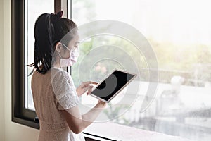 Asian woman wearing medical face mask, and using digital tablet