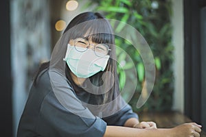 Asian woman wearing protection mask sitting at living room table