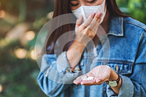 An asian woman wearing protective face mask and holding white medicine capsules in hand for Healthcare and Covid-