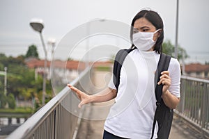 Asian woman wearing protective face mask scared disgusted walking on overcrossing city street. New lifestyle with Corona Virus