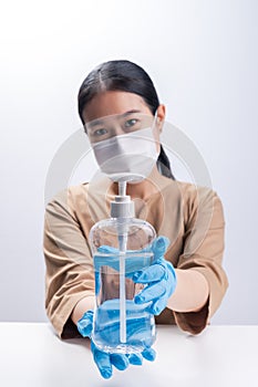 Asian woman wearing protective mask and presenting alcohol antiseptic gel