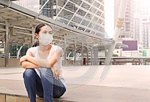 Asian woman wearing protective mask to protect virus, pollution and the flu sitting at public area