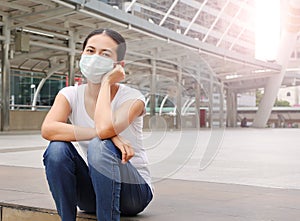 Asian woman wearing protective mask to protect virus, pollution and the flu sitting at public area