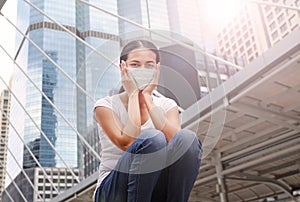 Asian woman wearing protective mask to protect virus, pollution and the flu sitting at public area