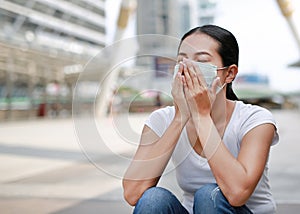 Asian woman wearing protective mask to protect virus, pollution and the flu sitting at public area