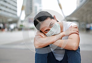 Asian woman wearing protective mask to protect virus, pollution and the flu sitting at public area