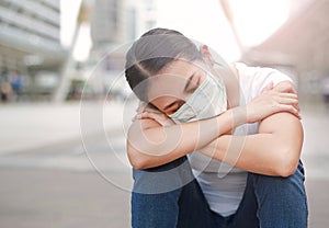 Asian woman wearing protective mask to protect virus, pollution and the flu sitting at public area