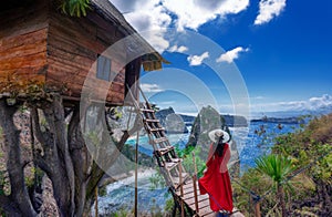 Asian woman wearing red dress visits tree house on the island of Nusa Penida, Bali, Indonesia photo