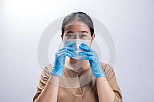 Asian woman is wearing sanitary gloves, mask on her face against coronavirus or COVID-19 disease. The Pollution Healthcare and