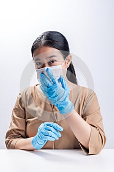 Asian woman is wearing sanitary gloves, mask on her face against coronavirus or COVID-19 disease. The Pollution Healthcare and