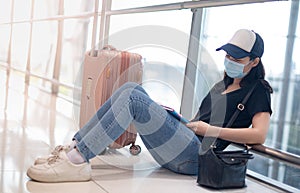 Asian woman wearing surgical mask feeling sad and depress for missed or cancelled flight for aboard to other place at the airport