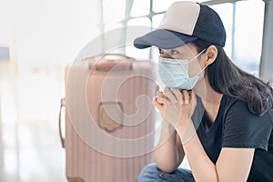 Asian woman wearing surgical mask feeling sad and depress for missed or cancelled flight for aboard to other place at the airport
