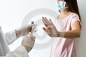 Asian woman wearing surgical mask refuse nurse injection or vaccination. Rejection of the vaccine, insecurity and fear concept