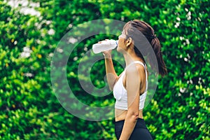 Asian woman wearing tight exercise clothes drinking water