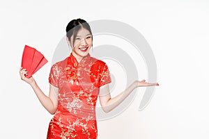 Asian woman wearing traditional cheongsam qipao dress showing something and holding angpao or red packet monetary gift isolated on