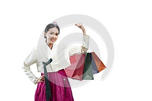 Asian woman wearing a traditional Korean national costume, Hanbok, standing while holding a shopping bag