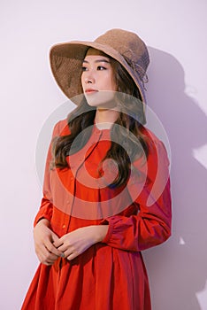 Asian woman wearing a wide-brimmed hat and summer clothes isolated on pink background