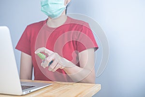 Asian woman wears protective mask using spray alcohol sanitizer cleaning a computer, to prevent the virus and bacterias. woman in
