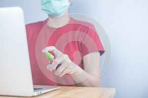 Asian woman wears protective mask using spray alcohol sanitizer cleaning a computer, to prevent the virus and bacterias. woman in