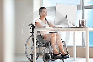 Asijský žena v invalidní vozík pracovní počítač v kancelář 