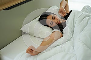 Asian woman on white pillow and bed sheet in bedroom relaxing on holiday stay home