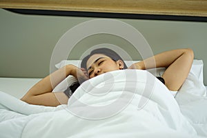 Asian woman on white pillow and bed sheet in bedroom relaxing on holiday stay home