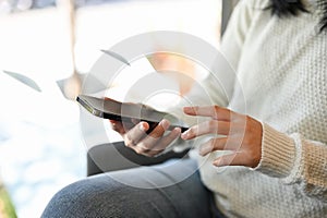 An Asian woman in white sweater using her smartphone while relaxing in the cafe. close-up image