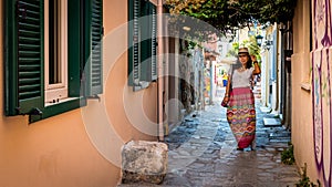 Asian woman in white t-shirt  in Athens in white hat and sarong standing in the middle of small road photo