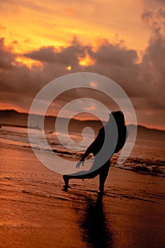 an Asian woman who is playing and dancing on the beach with strong waves