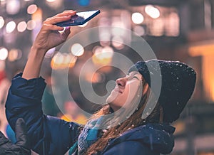 Asian woman in winter clothing tusing Mobile phone for communication ourdoor at night