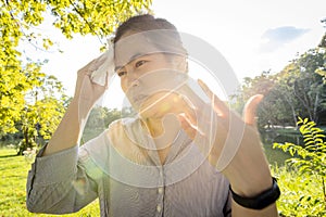 Asian woman wiping sweat on face with tissue paper suffer from sunburn very hot in summer weather problem feel faint, tired female