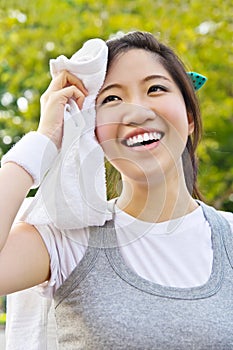 Asian woman wiping sweat with a towel after exerci