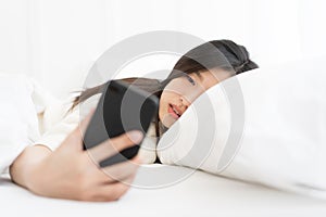 Asian Woman woke up by smartphone alarm clock and turning off snoozing phone alarm clock.