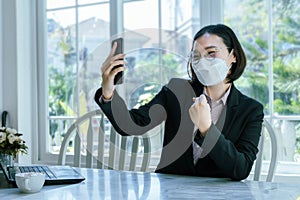 Asian woman in work clothes wearing masks Sit and look at the smartphone in the office, express emotions, be happy, achieve goals