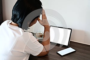 Asian woman work hard in front of tablet computer. she has headaches and stressed while working at home.