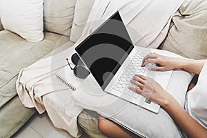 Asian woman work from home with laptop and headphone on sofa in living room