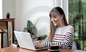 Asian woman work with laptop at home see outside house garden.digital transformation new normal lifestyle