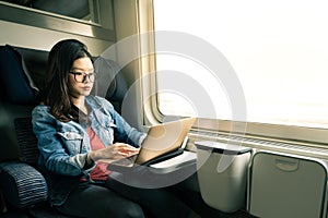 Asian woman work on laptop on train, business travel concept, warm light tone