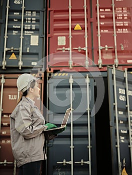 Asian woman worker holding Laptop and inspection container